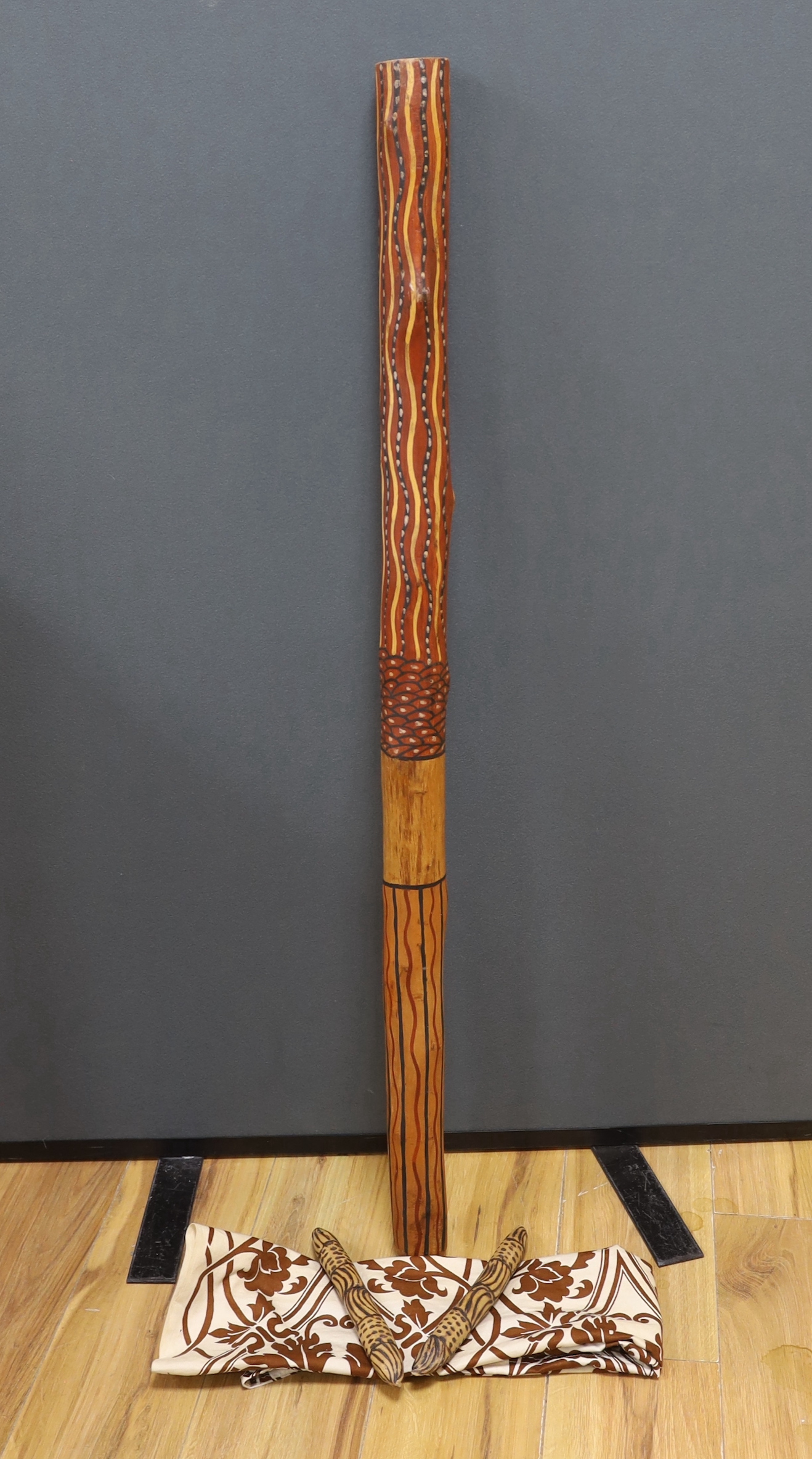 An Aboriginal decorated didgeridoo, Walpari tribe oil on canvas, a fabric painted panel and two decorated wooden sticks, canvas 50x61cm